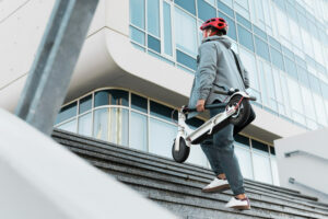 Homme montant escalier avec trottinette électrique