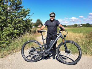 un homme qui se tient debout derrière son vélo électrique