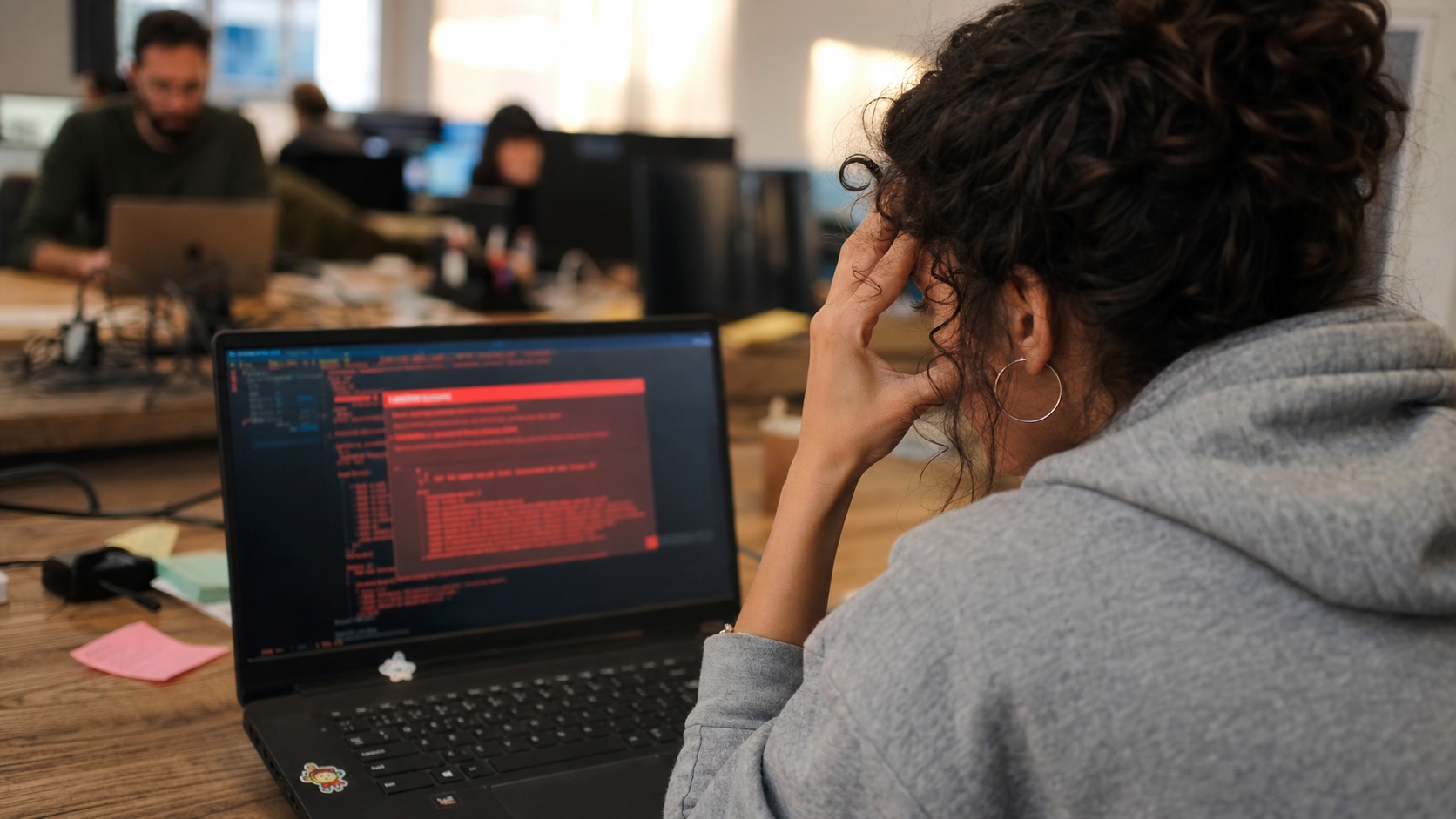 Développeur informatique constatant une erreur critique sur son écran de code dans un open-space parisien
